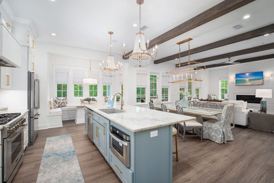 Your gourmet kitchen flows seamlessly into a light-filled dining and living space with elegant chandeliers and exposed beams creating the perfect gathering spot.