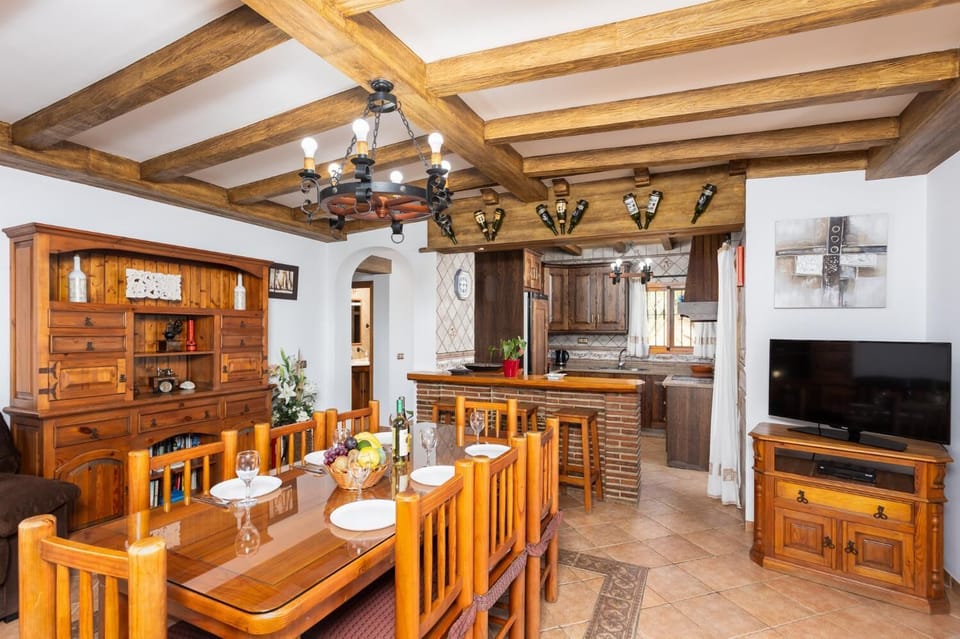 Open-plan living room with sofas, dining area, kitchen, ornamental fireplace, A/C, WiFi internet, and satellite TV