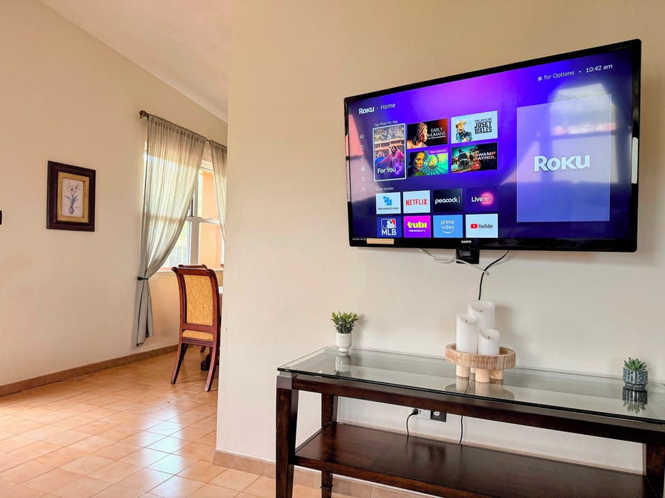Wall-mounted Roku TV with streaming apps in a bright, airy living space