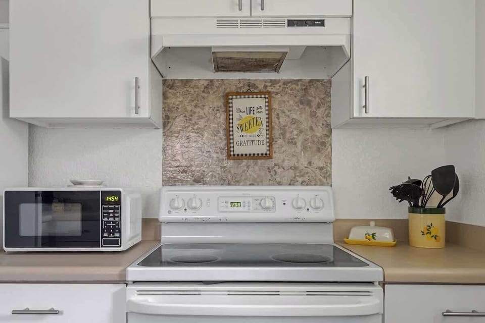 Bright, clean kitchen setup with microwave, stove, and plenty of cabinet storage for easy meal prep during your stay.