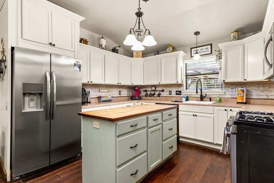 Cook with ease in a farmhouse kitchen featuring warm wood counters, full appliances, and open shelving. It’s charming, functional, and perfect for group meals.