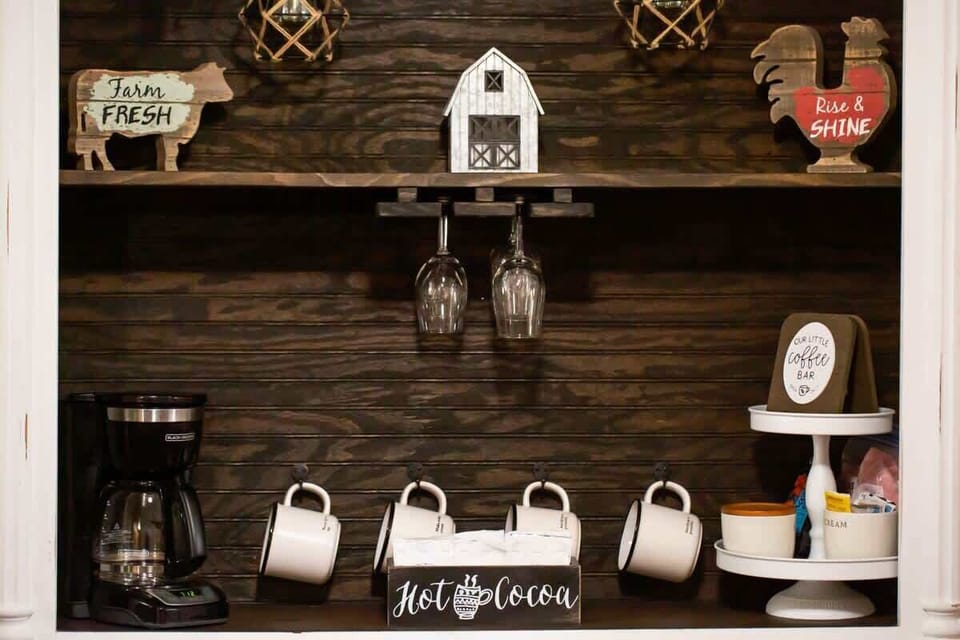 Start your day with a charming coffee station featuring mugs, shelves, and farmhouse style. It’s the perfect morning touch for every guest.