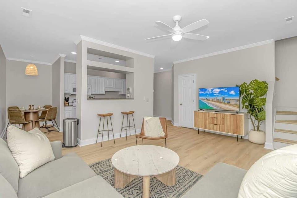 Relax in the open-concept living room, featuring plush seating, a large TV, and an inviting atmosphere for quality time with family and friends after your beach adventures. - The Myrtle - Myrtle Beach, SC