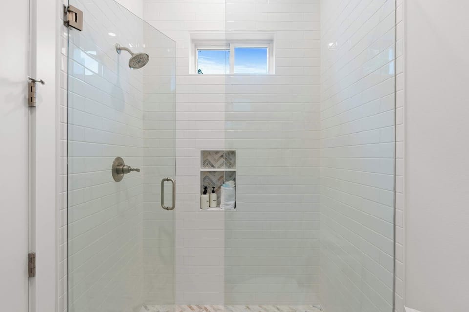 Indulge in a spa experience with a luxurious walk-in shower and high-end finishes in this elegant bathroom. - The Sandbar - Panama City Beach, FL