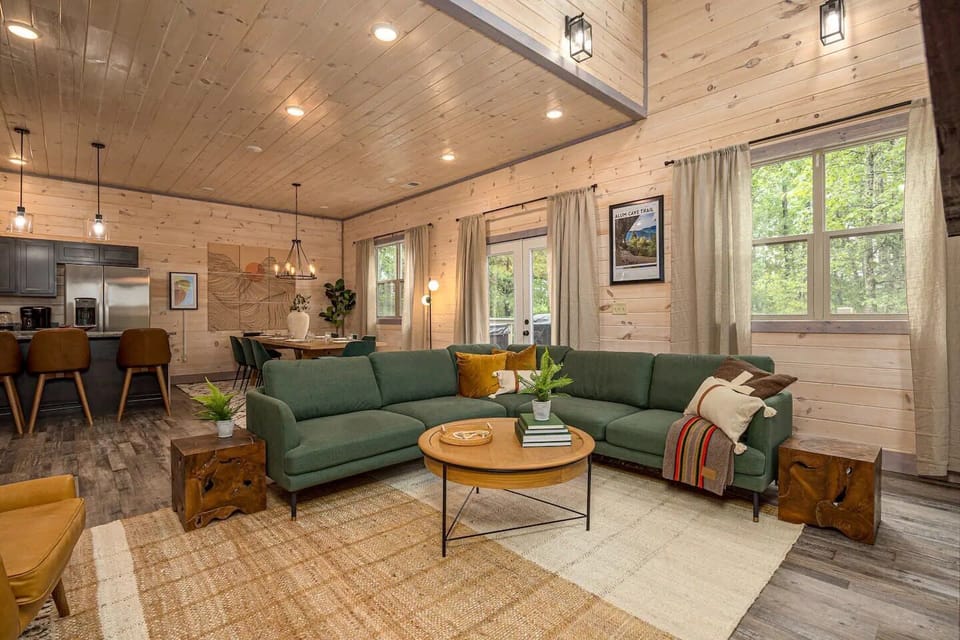 Unwind in the spacious open-concept living area featuring vaulted ceilings, a cozy fireplace, and plush seating—perfect for family gatherings. - The Smokey - Sevierville, TN