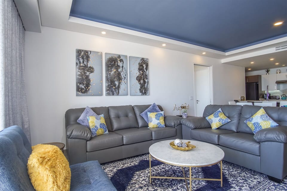 The living room is warm and inviting. Boasts comfortable seating, pillows and local artistry.