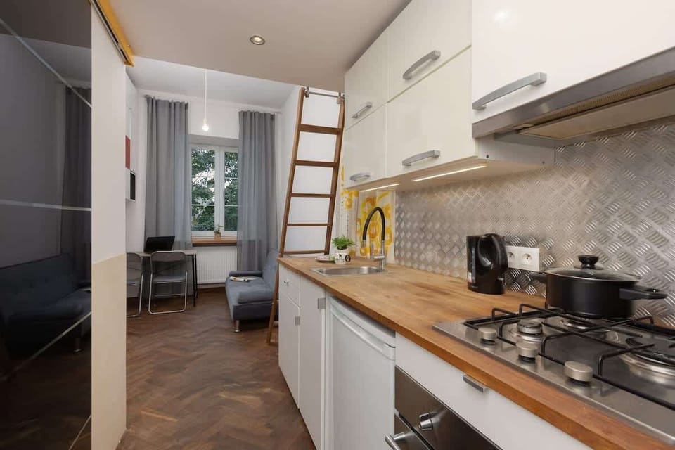 A modern kitchen corner with a built-in stove, mosaic backsplash, and sleek white cabinets.


