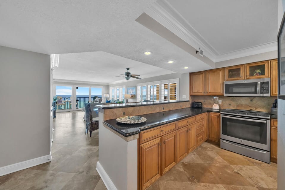 Your spacious kitchen flows into the living area, complete with granite counters, wood cabinetry, and stunning ocean views through floor-to-ceiling windows.