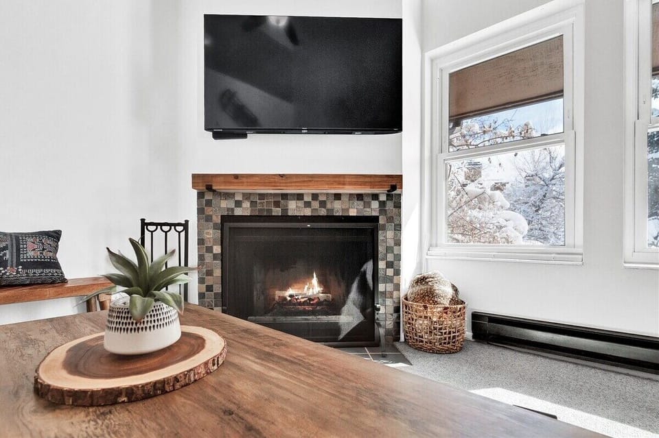 Relax by the fireplace while enjoying the wall-mounted TV and bright natural light from the nearby windows.