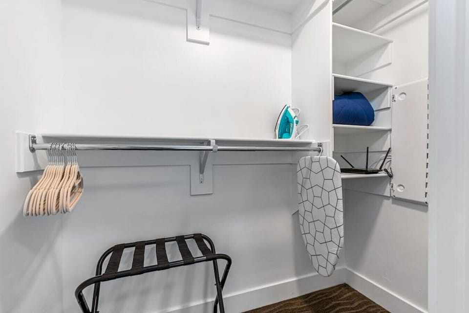Primary closet with plenty of space for your stay. Iron, Ironing board, hangers and luggage rack.