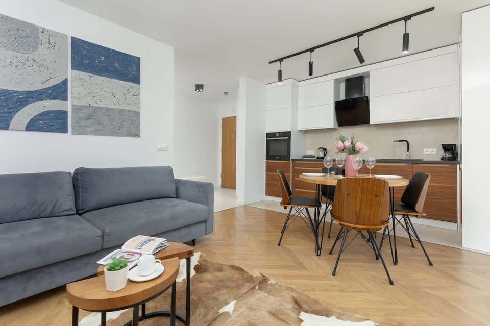 Another angle of the dining and living space, showing the dark wooden dining set and a gray sofa with a coffee table in front.