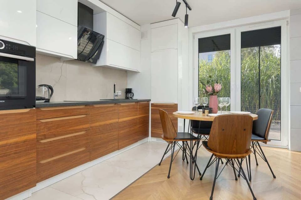 A contemporary kitchen with sleek wooden cabinetry and a minimalist design, blending seamlessly with the adjacent dining area.