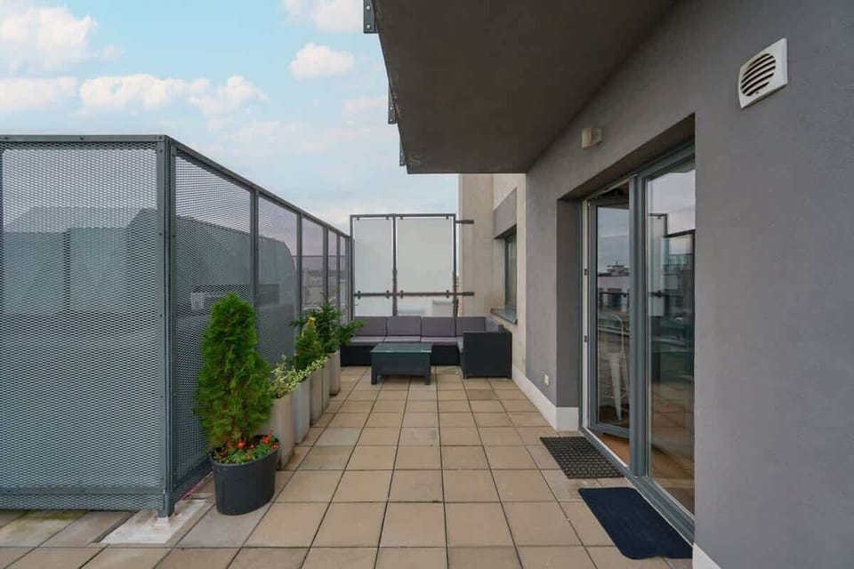 Another view of the terrace showcasing additional seating and greenery under a clear sky.

