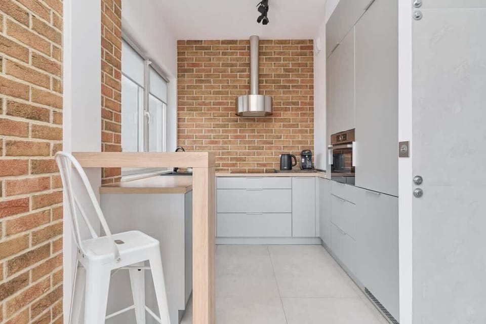 A kitchen view with a small bar area, brick accents, and modern white cabinets.



