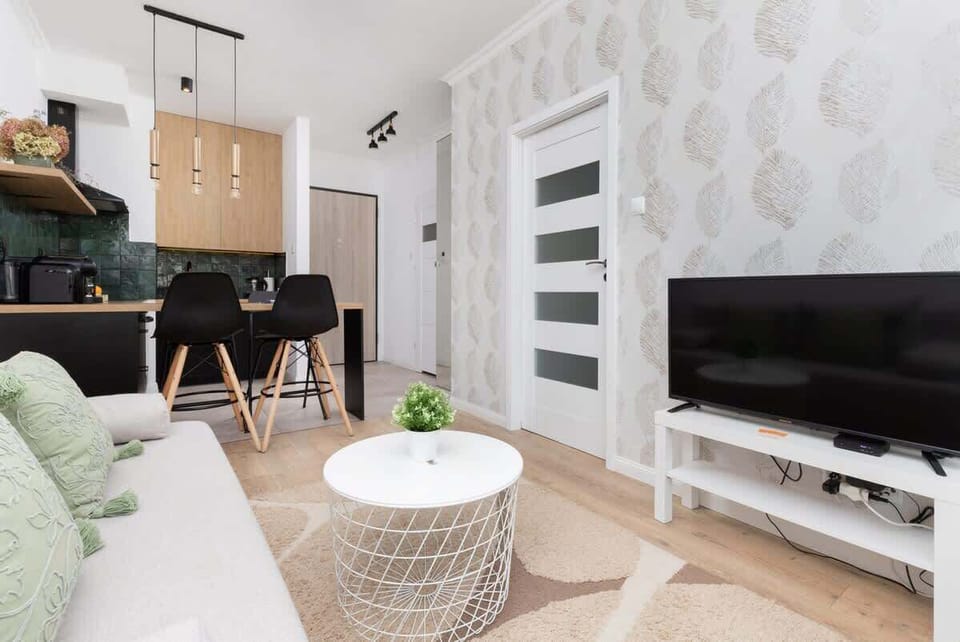 A bright living area showing a large TV, sectional sofa, and a modern yet inviting decor style.

