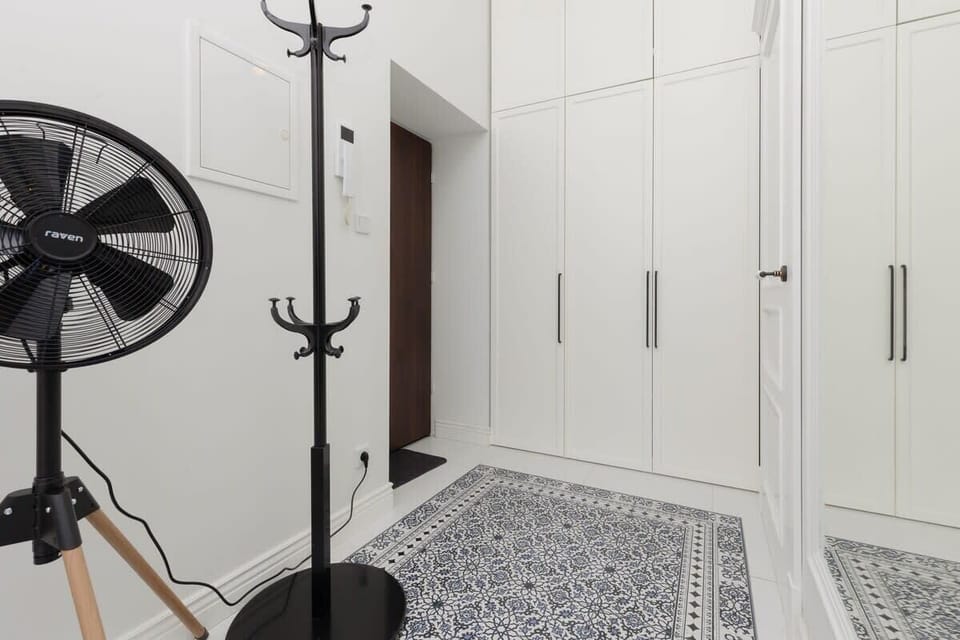 An entryway space featuring a coat rack, white wardrobe cabinets, and patterned tile flooring.