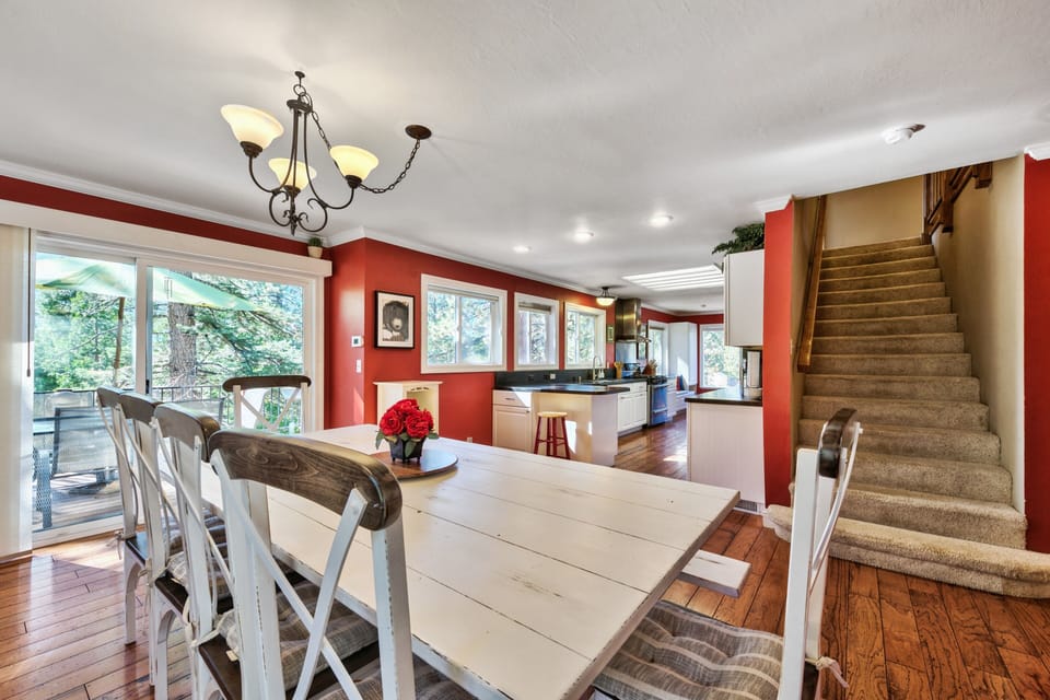 Gather around your spacious farmhouse dining table where warm red walls and natural light create the perfect setting for memorable meals together.