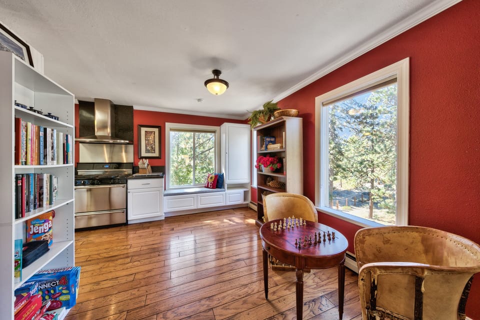 Cozy up in this charming space where red walls embrace you, chess awaits your next move, and books invite quiet moments.