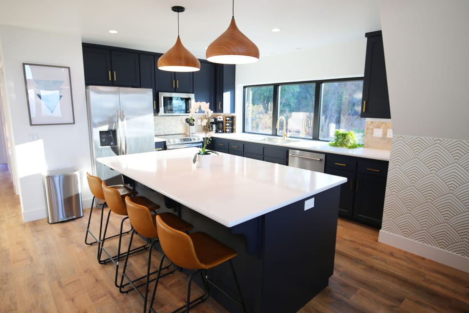 Quartz countertops, gold backsplash and handles, with stainless appliances. 