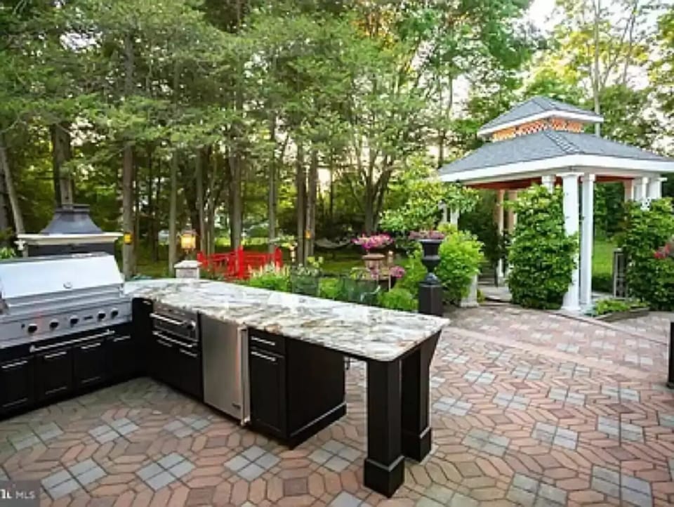 Outdoor kitchen has fridge, large bread warmer, grill, stove, sink