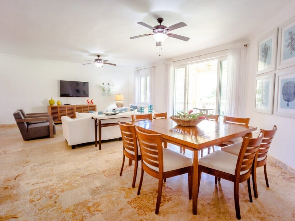 Large modern  living and dining area with AC, flat screen TV, and ceiling fans.