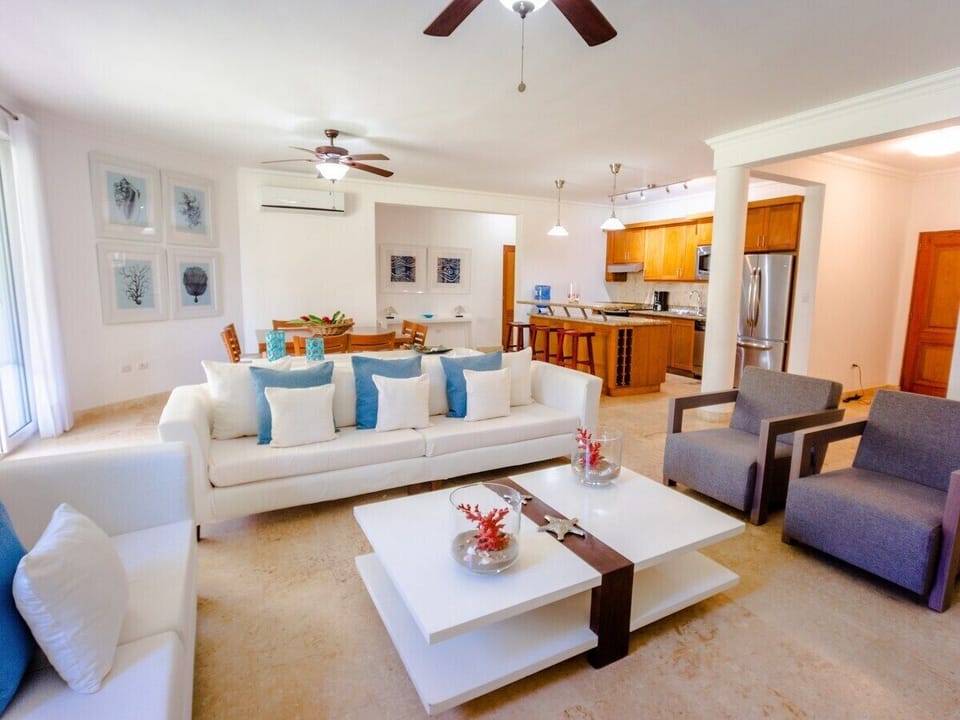 Large modern  living and dining area with AC, flat screen TV, and ceiling fans.