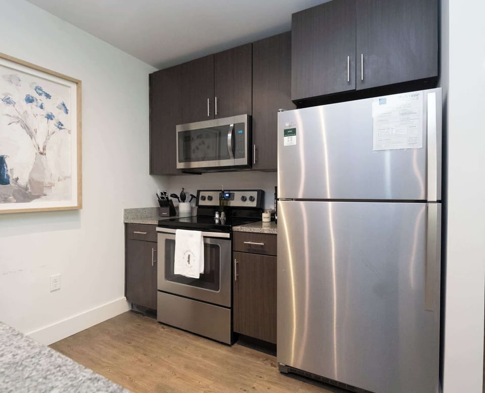 A functional breakfast bar with three woven stools, providing a casual transition into the modern kitchen area.