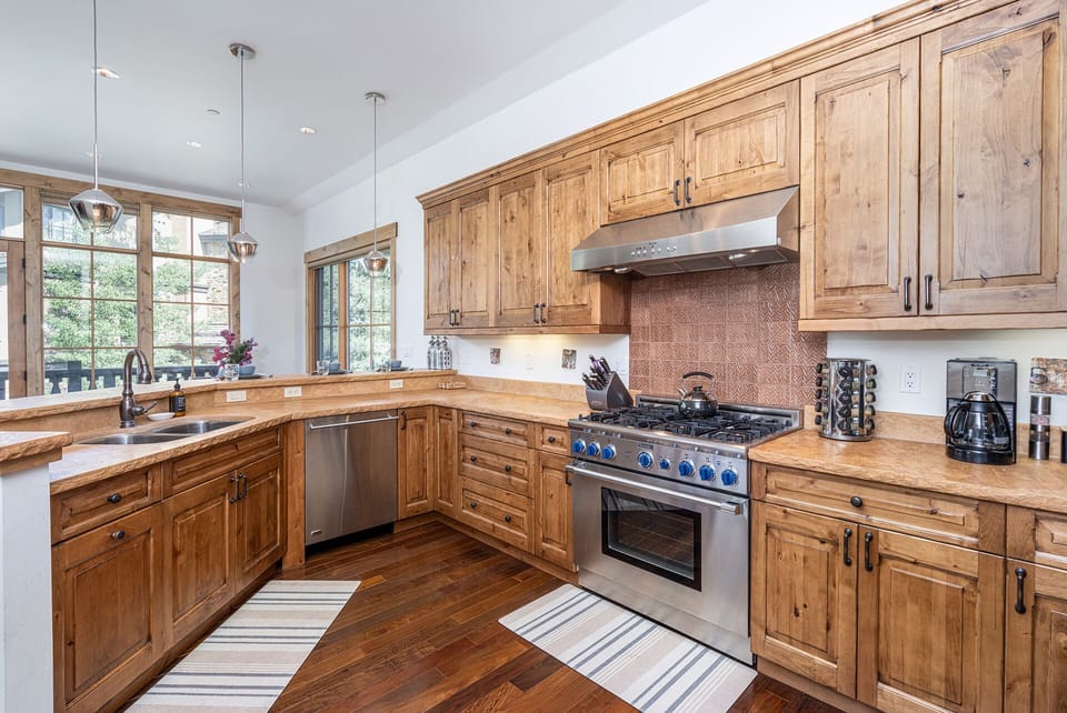Fully stocked spacious kitchen with modern stainless steel appliances and a gas range.
