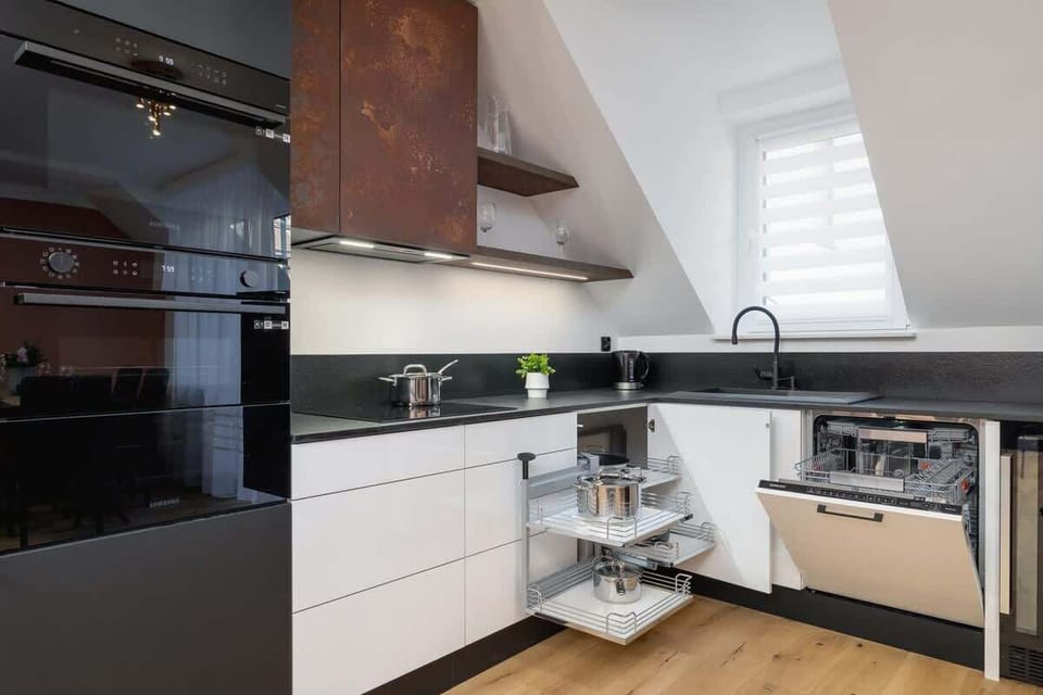 A stylish corner kitchen with white cabinetry, wooden accents, and a sloped ceiling design.