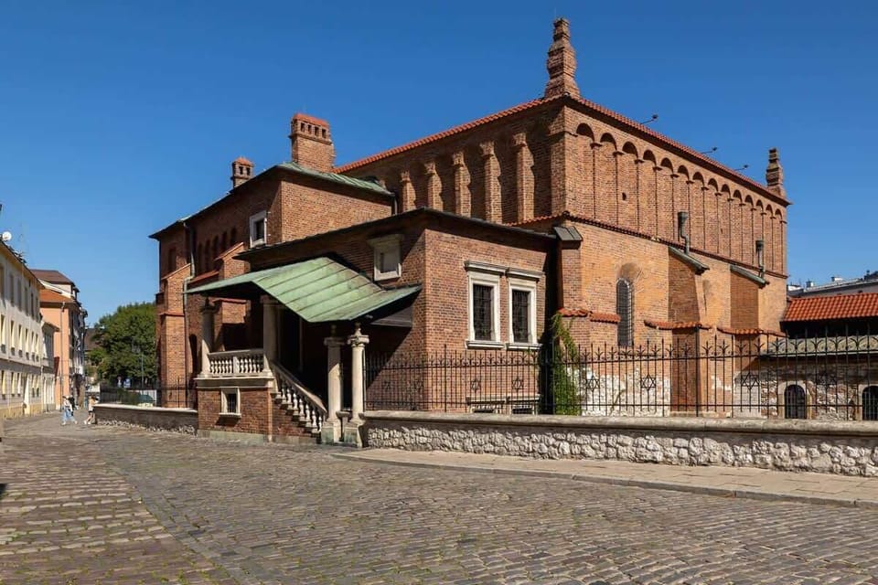 A historical red-brick building standing on a cobblestone street, likely a landmark or a nearby attraction.