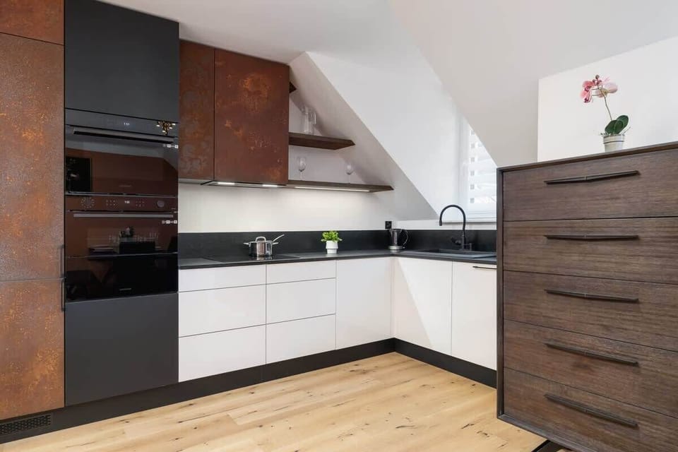 A stylish corner kitchen with white cabinetry, wooden accents, and a sloped ceiling design.