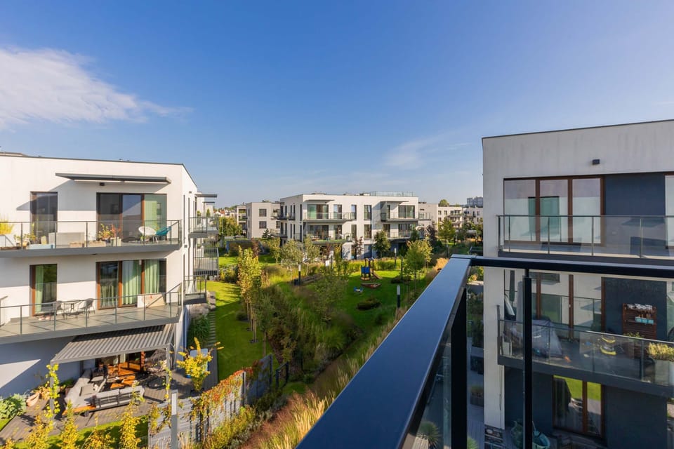 An aerial view of a modern residential complex with low-rise buildings and lush green spaces, showcasing an attractive and well-maintained neighborhood.