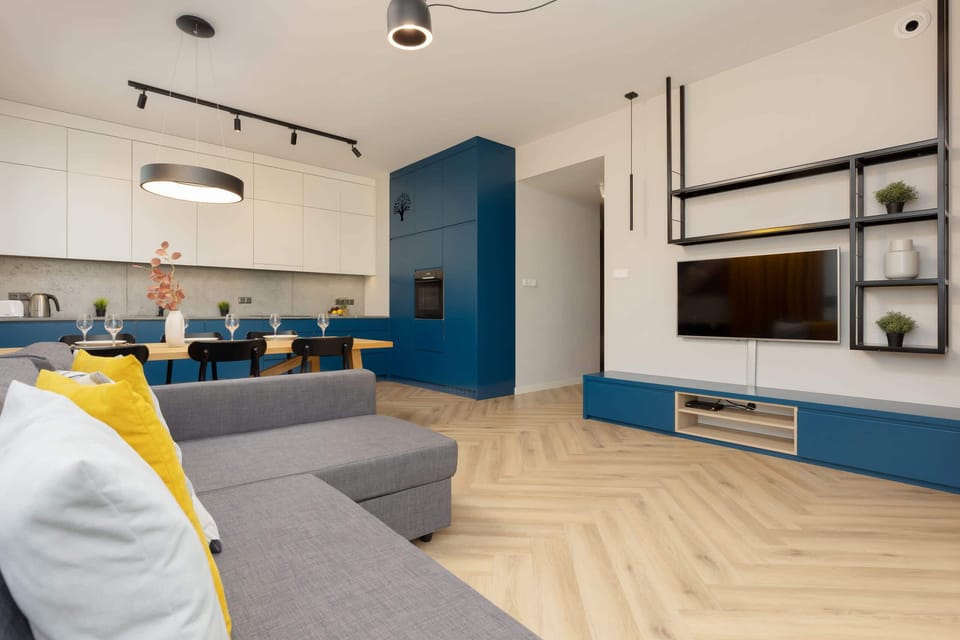 A spacious living room featuring a gray L-shaped sofa and mustard-yellow curtains that add a vibrant touch, making the room feel warm and inviting.