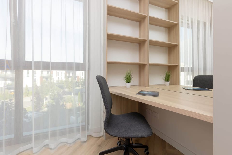 A bright home office space with a desk and chair, featuring large windows that let in natural light, making it a perfect area for working from home.