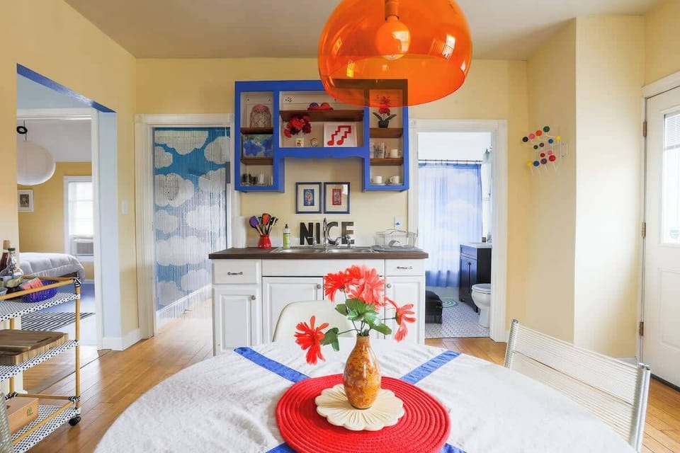 Bright kitchen with electric blue cabinetry and eating space.

To the left is a the laundry room with washer and dryer, to the right is the bathroom.