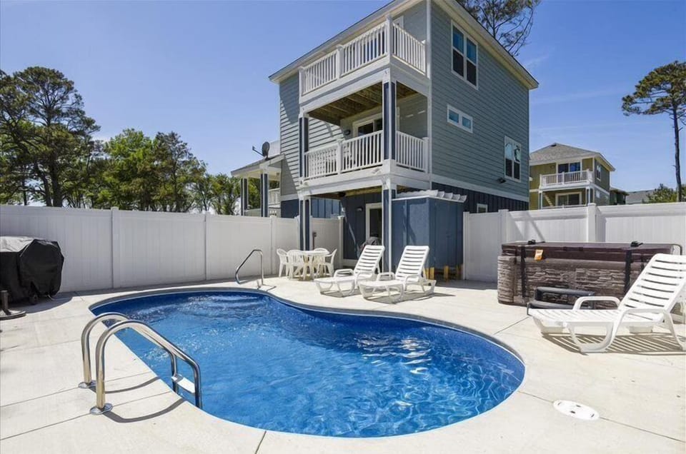 A delightful poolside oasis with a clear view of the house's rear facade.