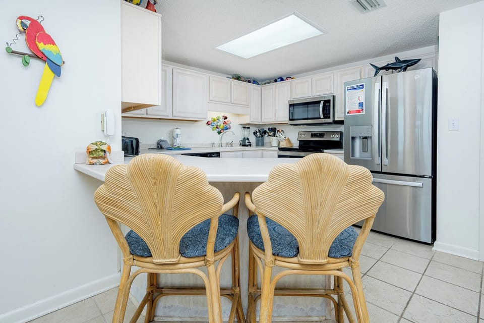Gather around the stylish bar stools for casual meals in this inviting kitchen space, featuring stainless appliances