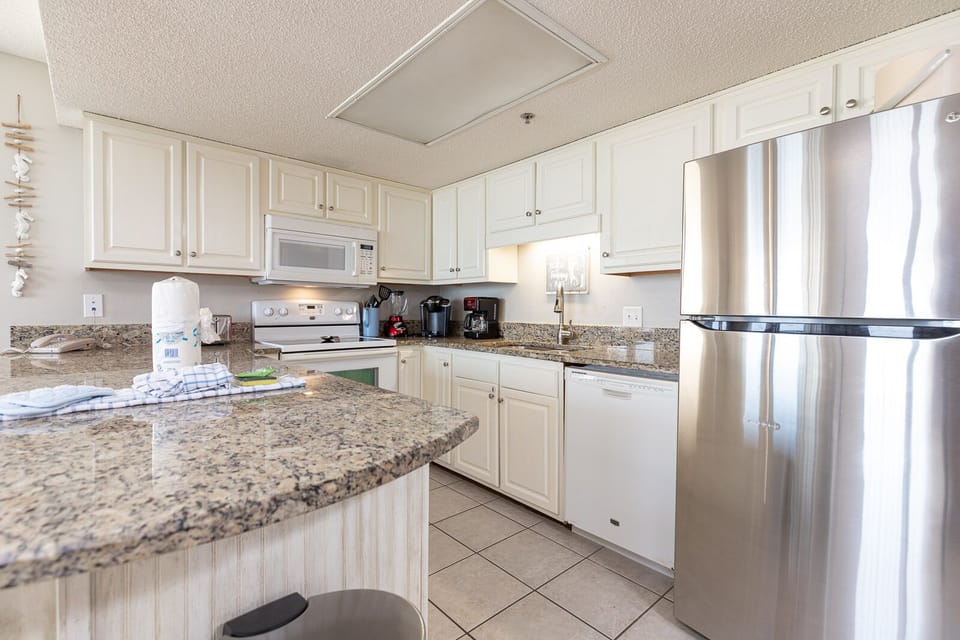 The kitchen featuring white cabinetry, granite countertops, and a convenient breakfast bar with seating for casual dining