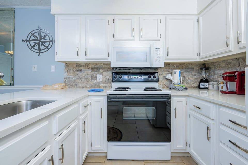 This kitchen features white cabinetry, stainless appliances, and a Keurig coffee maker for a delightful cooking experience