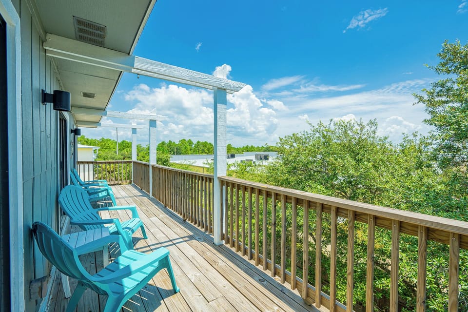 Relax on the turquoise chairs of this inviting balcony, offering a serene view of lush greenery under a bright blue sky