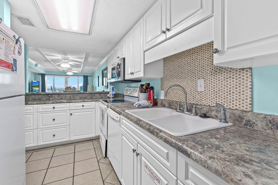Cheerful kitchen featuring modern appliances, stylish countertops, and a lovely view of the beach outside