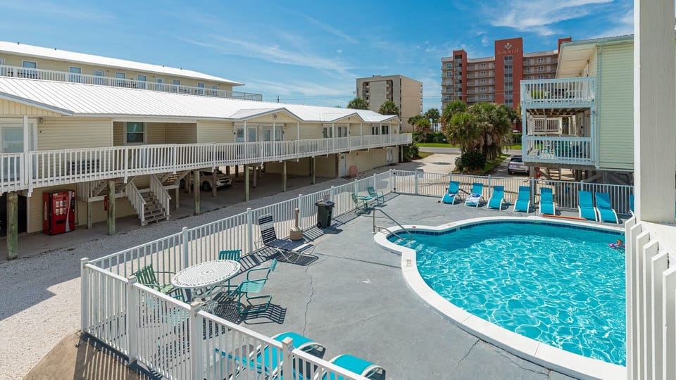 The inviting pool area features a sparkling blue pool surrounded by comfortable lounge chairs, perfect for relaxation and fun