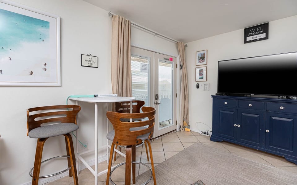 This cozy living area features a large TV, stylish bar stool seating area, and easy access to the outdoor space
