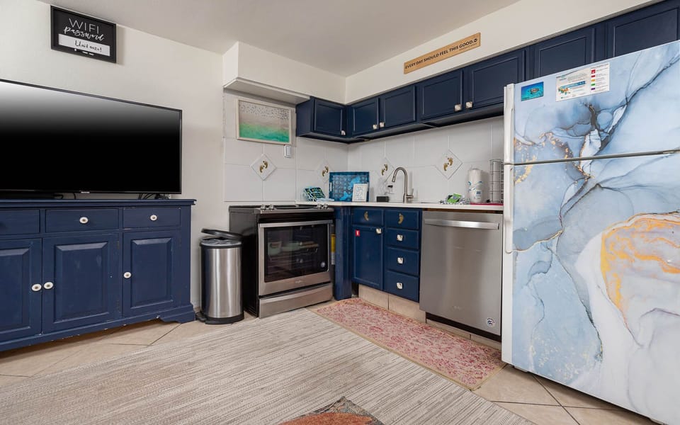 The kitchen features stylish blue cabinets, stainless appliances, and a TV, creating a space perfect cooking and entertaining