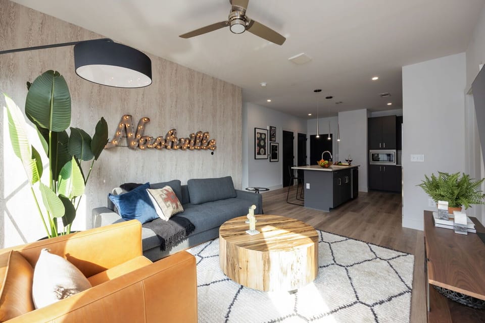 Modern open concept living area with floor to ceiling windows, designer furniture, smart TV, and access to private patio.