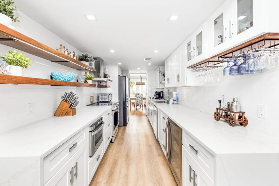 Your spacious galley kitchen features sleek white cabinets, warm wood shelving, and premium appliances for effortless meal preparation.