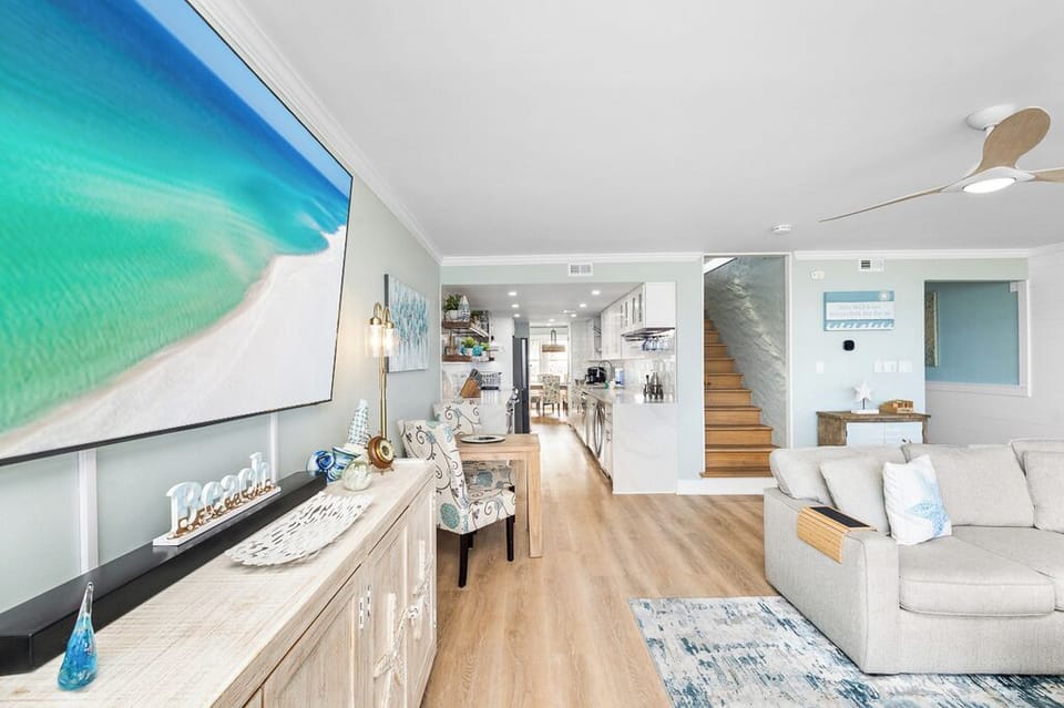 Relax in your bright, coastal-inspired space with ocean artwork, modern kitchen, and comfortable seating that makes you feel at home.