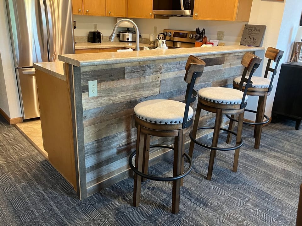 - Breakfast bar with rustic wood paneling detail   - Padded bar stools provide comfortable seating   - Great spot for casual dining or morning coffee