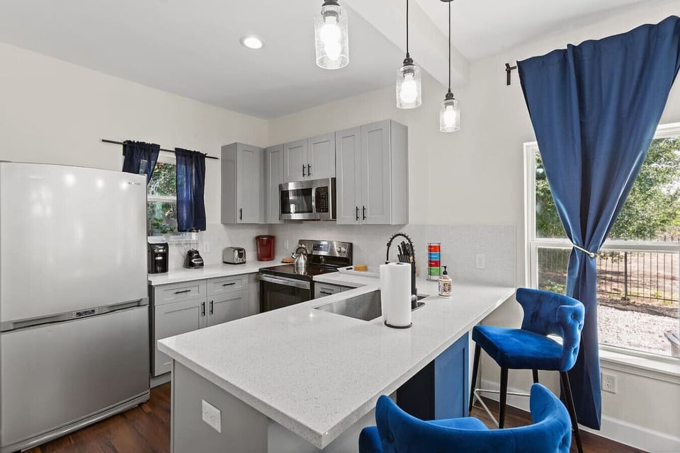 Another view of the kitchen showing bar seating, ample counter space, and large windows that fill the space with natural light.