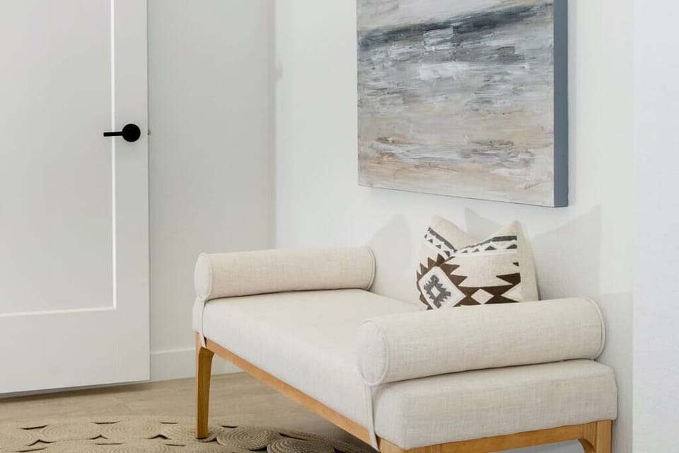 Modern entryway bench with patterned pillows and abstract wall art